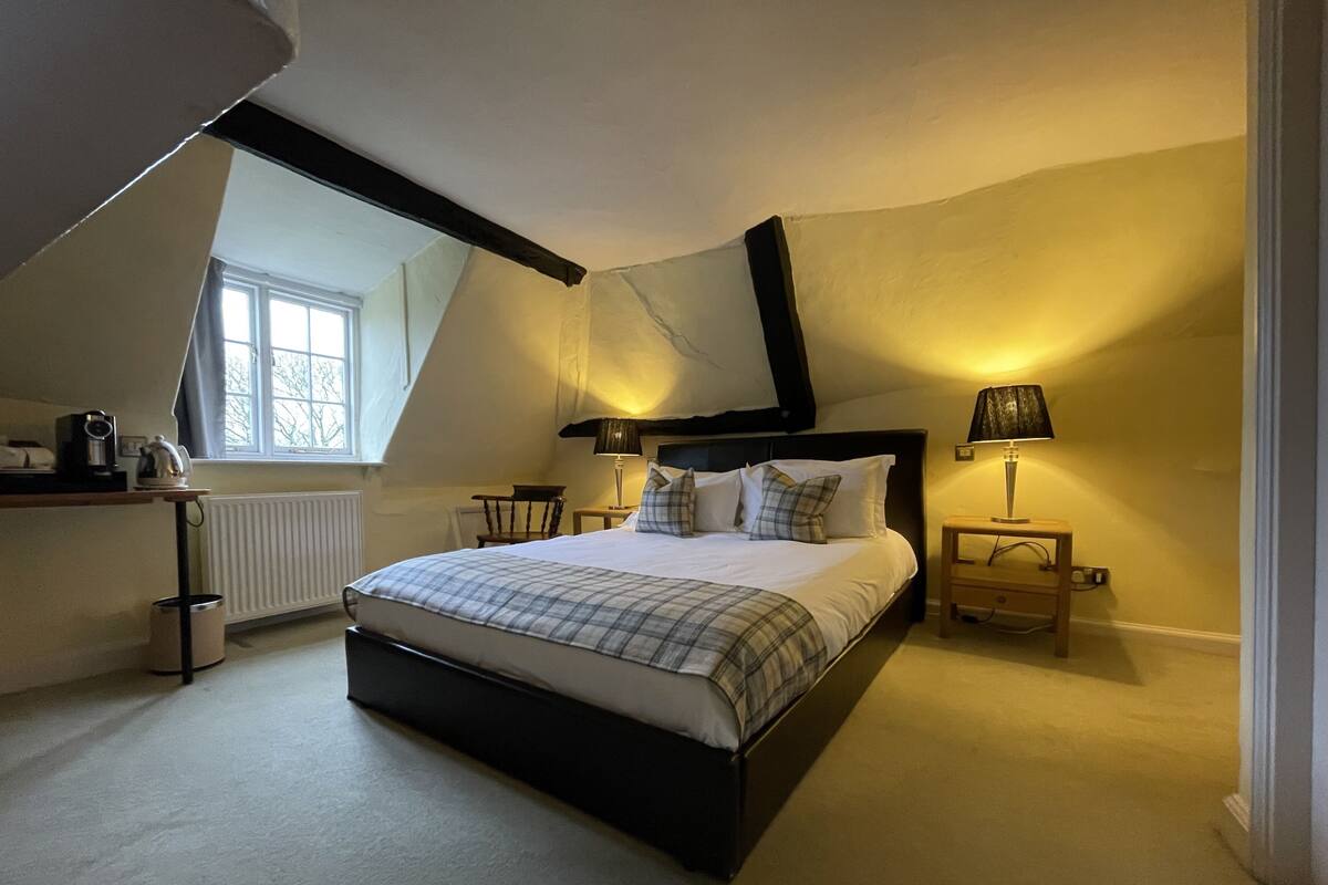A bedroom with a large bed, two bedside tables, a window, and a radiator.