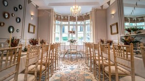 Un comedor formal con candelabro, sillas de madera y alfombra estampada.