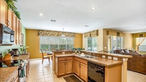 A modern kitchen with granite countertops, wooden cabinets, and a built-in dishwasher. - Spacious And Relaxing Home With South Facing Pool 6 Bedroom Home by RedAwning (Davenport)