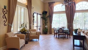 A spacious living room with a dining area, large windows with curtains, and a ceiling fan. - Spacious And Relaxing Home With South Facing Pool 6 Bedroom Home by RedAwning (Davenport)