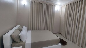 Un dormitorio con cama, cortinas y una lámpara.
