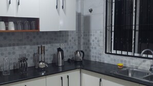 Una cocina con armarios blancos, encimera negra y ventana con barrotes.