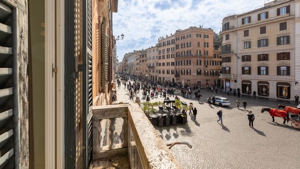 Escena de carrer animada amb edificis històrics, paviment de lladroncs i un carrossa tirat per cavalls.