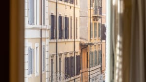 Vista des d'una finestra amb cortina, que mostra una escena urbana amb edificis i un cartell de restaurant.