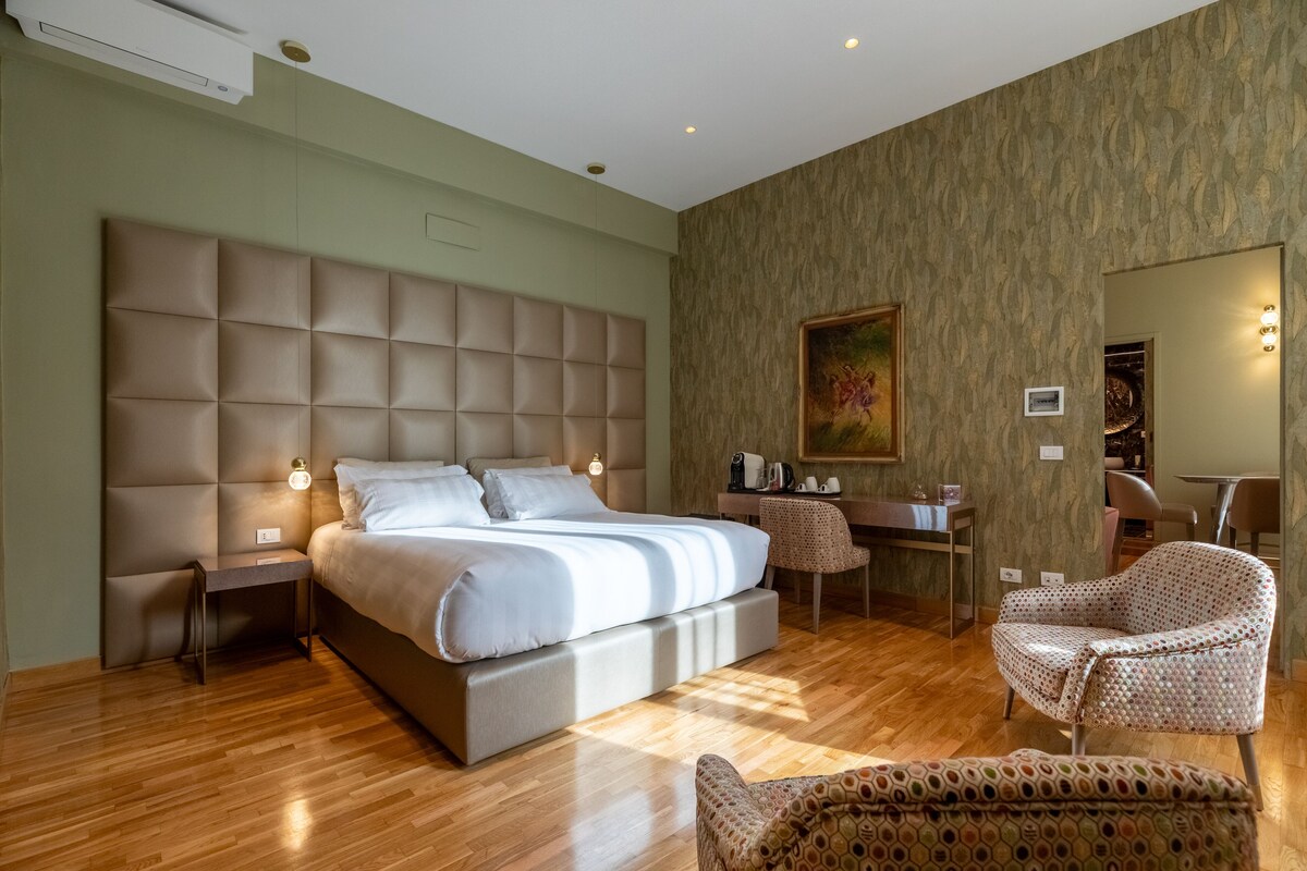 A modern hotel room with a large bed, a desk, and a chair.