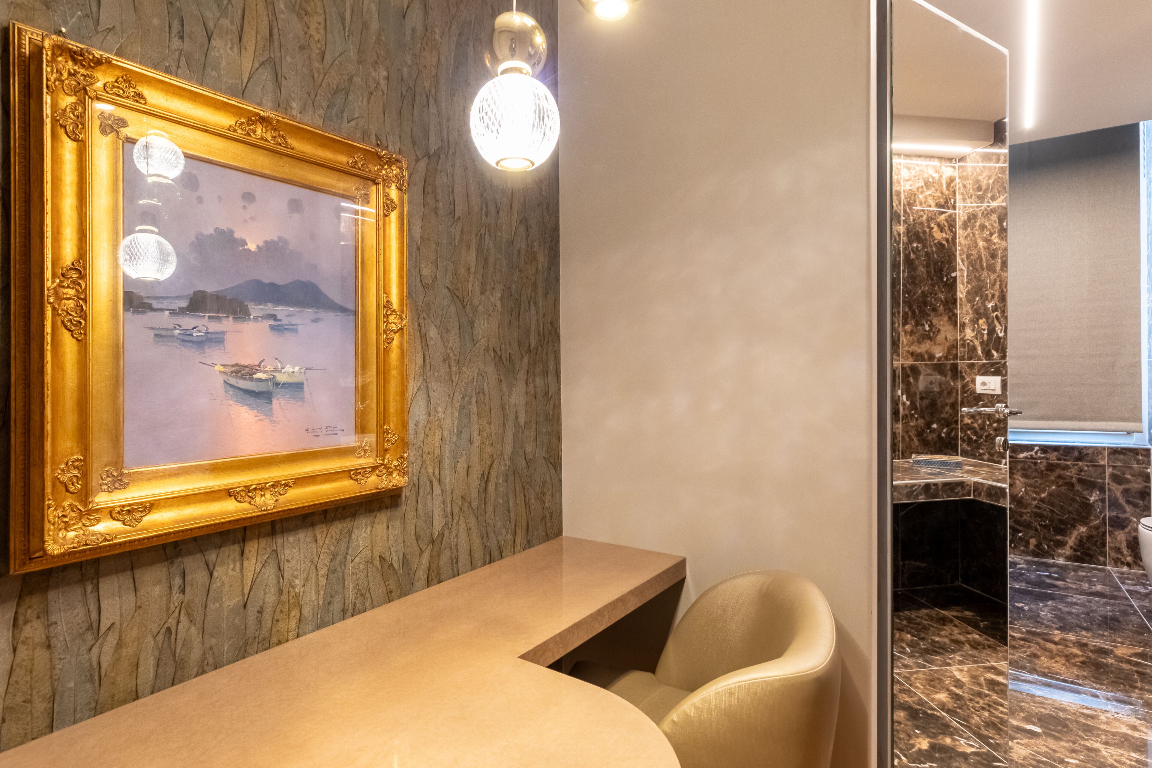 A reception area with a marble wall, a framed artwork, a reception desk, and a seating area.