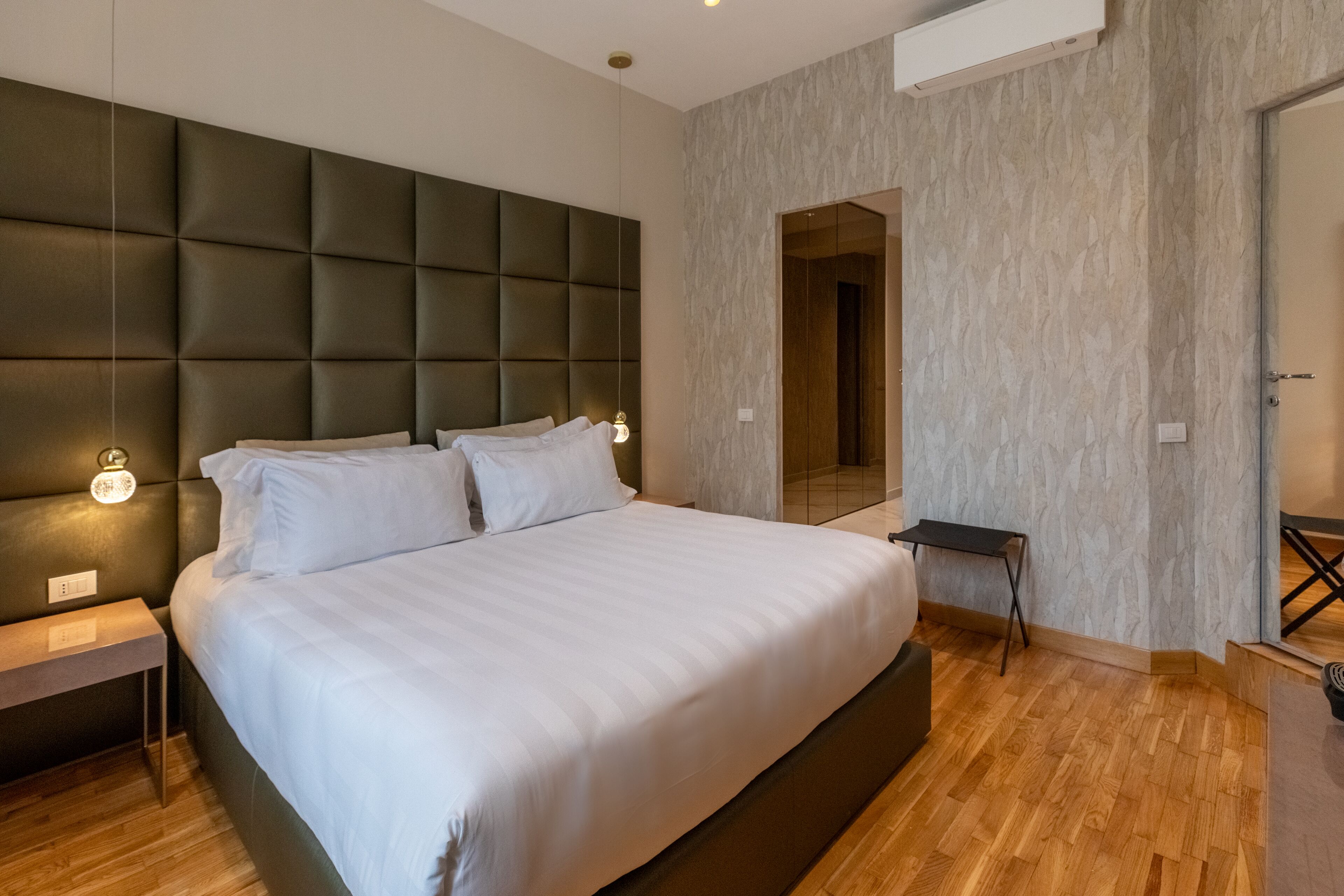 A modern bedroom with a large bed, a headboard, bedside tables, and a small table.