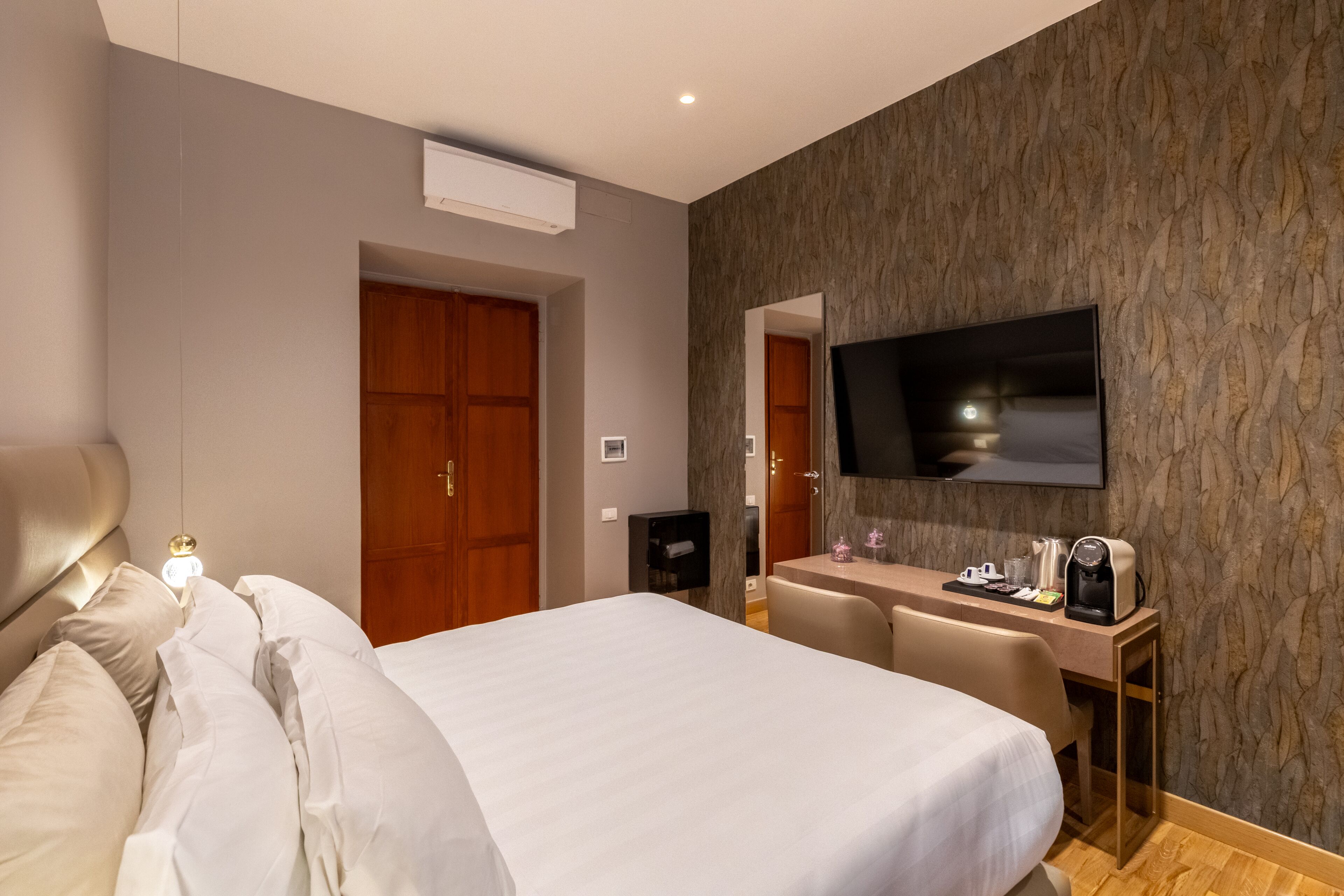 A hotel room with a bed, a desk, a chair, a TV, and a coffee maker.