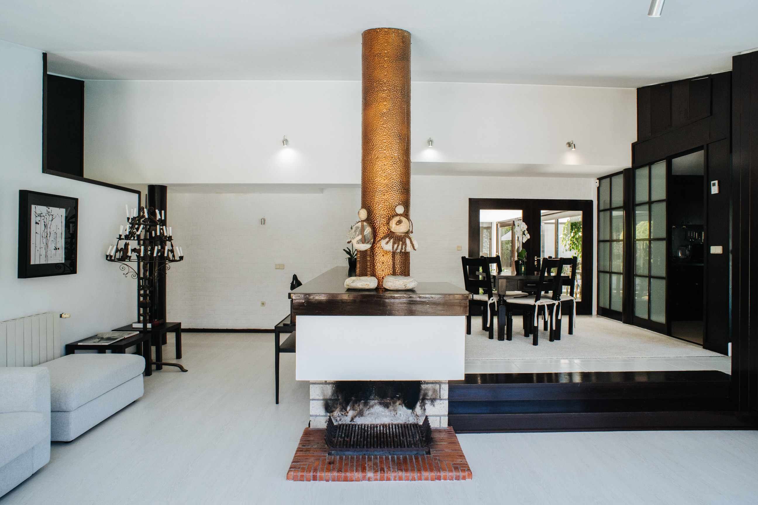Una sala de estar moderna con chimenea, un comedor y un ventanal grande.