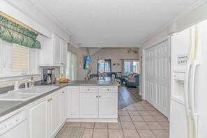 A spacious kitchen with white cabinetry, a large island, and a refrigerator.