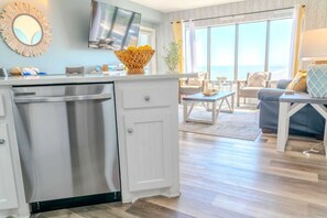 A modern kitchen with a dishwasher, a dining area with a table and chairs, and a large window offering a view.