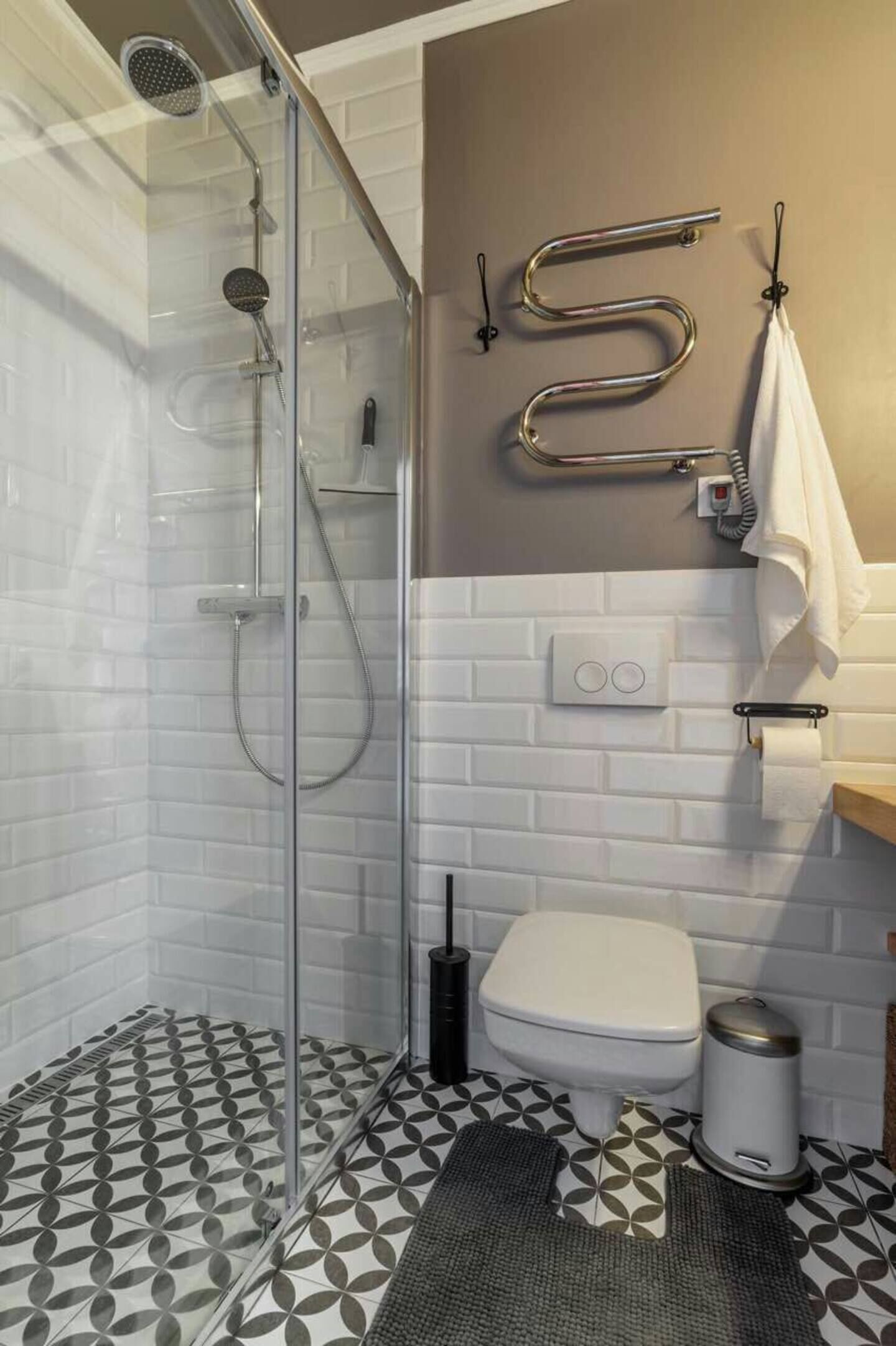 A bathroom with a glass shower enclosure, a toilet, a bidet, and a towel rack.