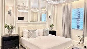 Quarto moderno com uma cama grande, um candelabro e vista para o exterior pela janela.