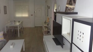 Ein Zimmer mit Esstisch, Stühlen, einem weißen Schrank und einer Tür zu einem anderen Raum.