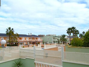 Une cour d’hôtel avec une piscine, des palmiers et une clôture blanche.