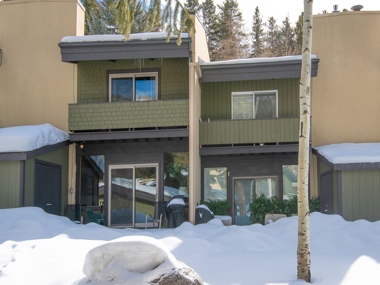 Un bâtiment à deux étages, avec une façade verte et un balcon. Il y a de la neige sur le toit et sur le sol.