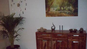 Une pièce comprenant un meuble en bois, une horloge, un tableau et une plante en pot.