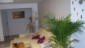 Una sala de estar con un sofá beige, una mesa de centro de madera y una planta verde grande.