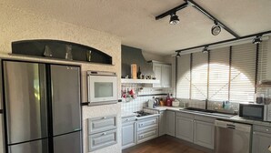 A modern kitchen with stainless steel appliances, white cabinetry, and a wooden floor. - The Swedish Villa with heated interior pool (Perpignan)