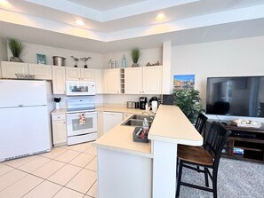 A compact kitchen with white cabinetry, a built-in oven, a microwave, and a coffee maker.
