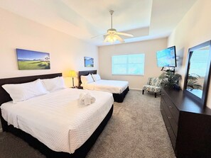 A hotel room with two beds, a ceiling fan, a TV, a chair, and artwork on the walls. - Right Direction Rentals 1 Bedroom Villa 8272 (Port St. Lucie)