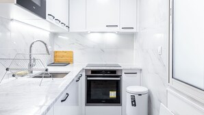 A modern kitchen with white cabinetry, a built-in oven, and a stainless steel sink.