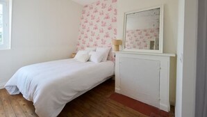 Een slaapkamer met een enkel bed, een witte radiator en een muur met bloemenbehang.