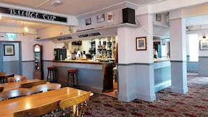 A bar area with a counter, stools, and a patterned carpet. - The Railway Inn (Malvern)