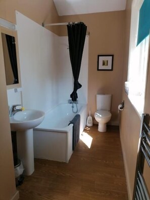 A compact bathroom with a bathtub, sink, and toilet. - The Railway Inn (Malvern)