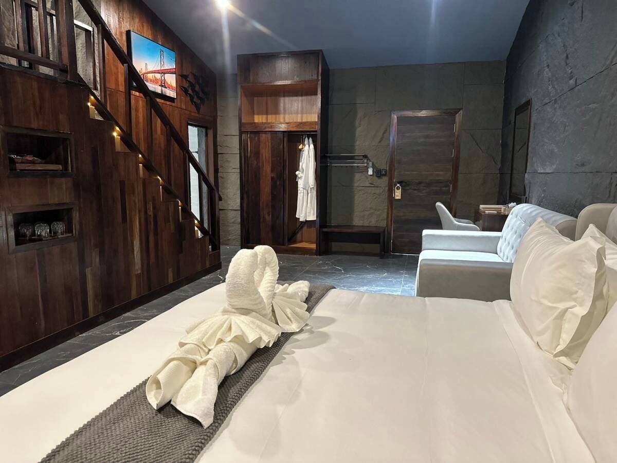 Una habitación de hotel con una cama grande, una zona de estar y un armario.