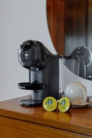 Una cafetera con dos cápsulas de café sobre una superficie de madera.