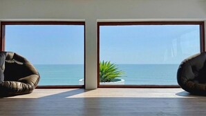 Una habitación con ventanas amplias, dos sillones de cuero, una planta pequeña y suelo de madera.