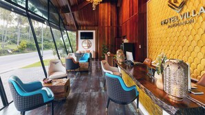 Vestíbulo de hotel con interior de madera, una recepción y un amplio ventanal con vistas al exterior.