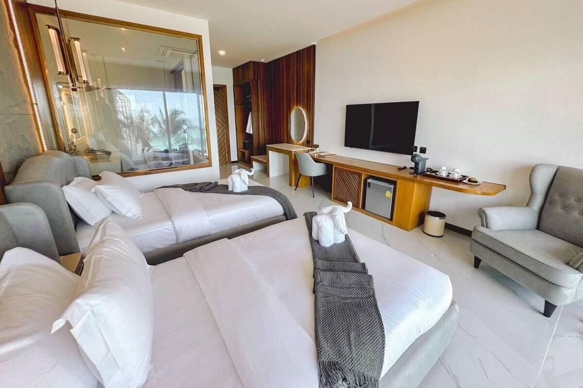 Ein Hotelzimmer mit zwei Betten, einem Schreibtisch, einem Fernseher und einer Sitzecke.