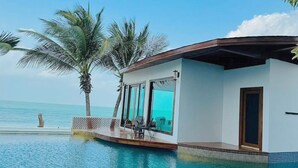 Un moderno resort con piscina, palmeras y una vista despejada del océano.
