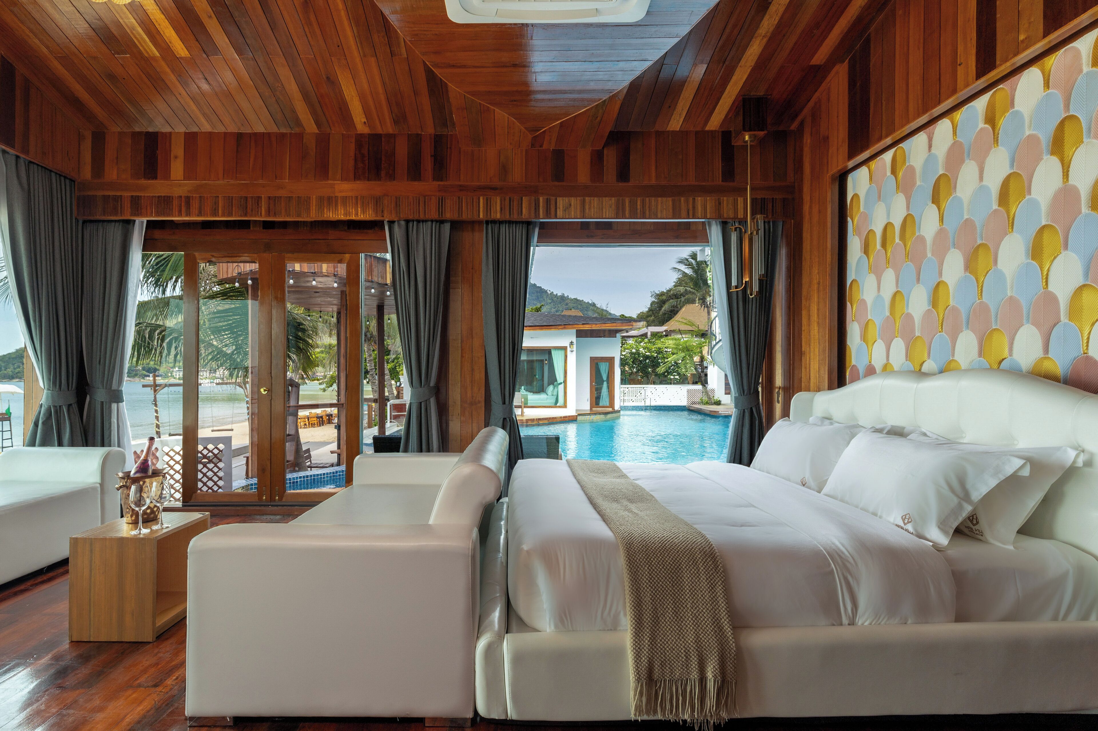 Ein geräumiges Schlafzimmer mit einem großen Bett, einer Sitzecke und Blick auf einen Pool und Berge.