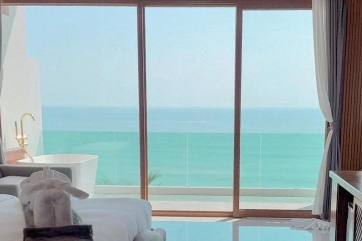 Habitación de hotel con un amplio ventanal corredero que da a un balcón con vistas al océano.