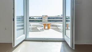 Ein Zimmer mit einer großen Glasschiebetür, die auf eine Terrasse mit Tisch und Stühlen führt.