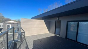 Ein modernes Gebäude mit flachem Dach, einer Holzterrasse und einer Glastür.