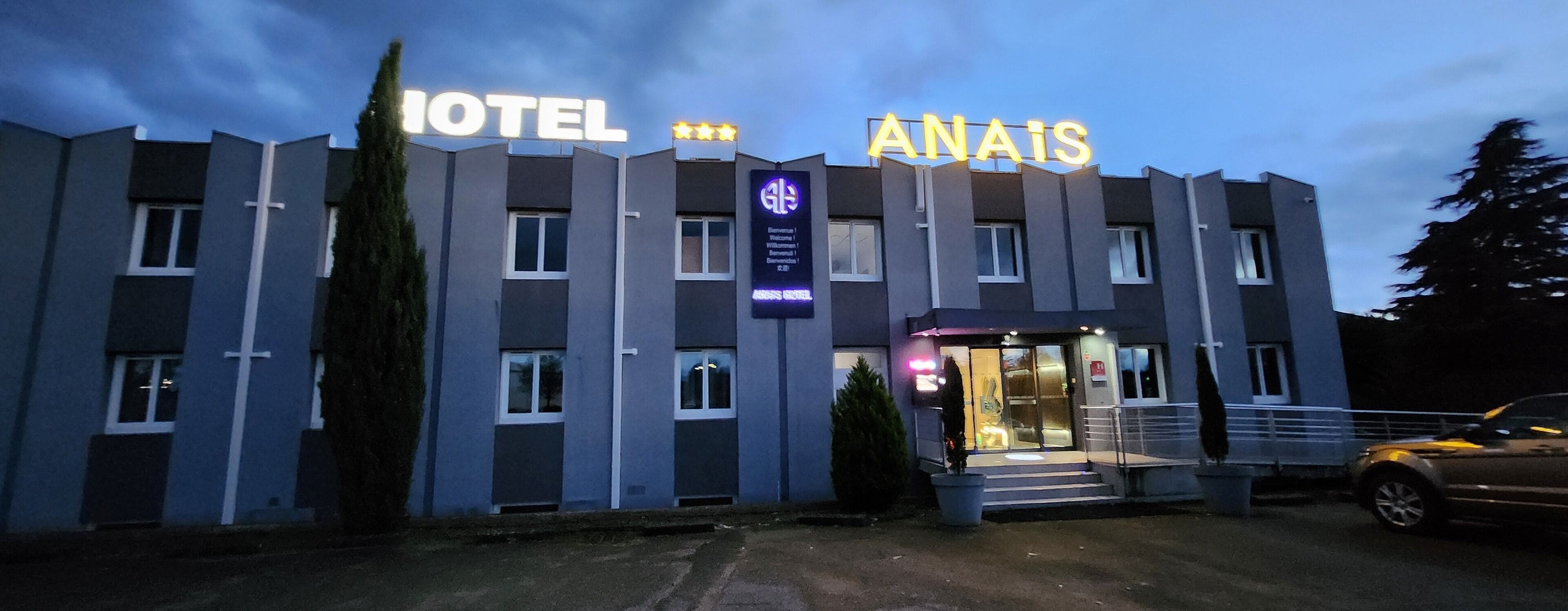 A hotel with a modern design, featuring a prominent entrance with glass doors and a signboard displaying the hotel's name and amenities.