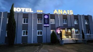 A hotel with a modern design, featuring a prominent entrance with glass doors and a signboard displaying the hotel's name and amenities.