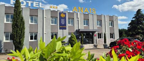 Un moderno edificio de hotel con un letrero que dice "ANAYS HOTEL" y un cartel de bienvenida en varios idiomas.