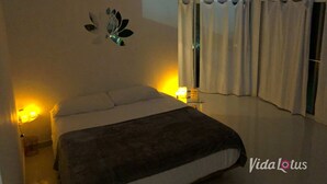 A bedroom with a bed, a ceiling fan, a wall-mounted light fixture, and a window with curtains.