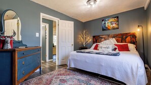 A bedroom with a bed, dresser, and a mirror.