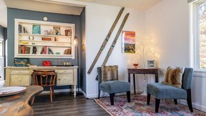 A cozy living room with a bookshelf, two armchairs, a small table, and a window with a view.