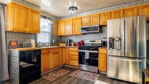 A kitchen with wooden cabinets, stainless steel appliances, and patterned backsplash.