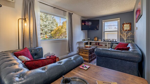 A cozy living room with leather sofas, a wooden coffee table, and a television mounted on the wall.