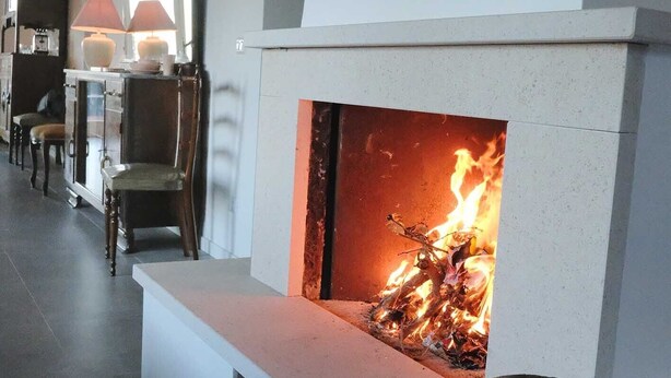 A modern living room with a fireplace, a framed artwork above it, and a stone bowl on the mantel. - casa Rosa milo (Milo)
