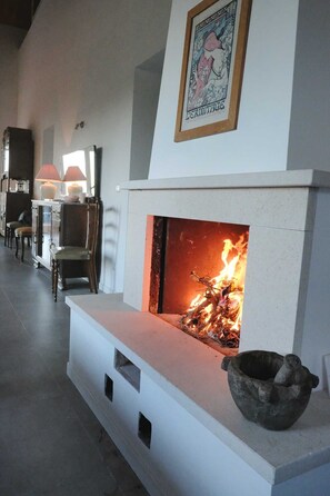 A modern living room with a fireplace, a framed artwork above it, and a stone bowl on the mantel. - casa Rosa milo (Milo)