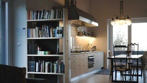 A modern kitchen with a built-in oven, a dining table with chairs, and a bookshelf filled with books. - casa Rosa milo (Milo)